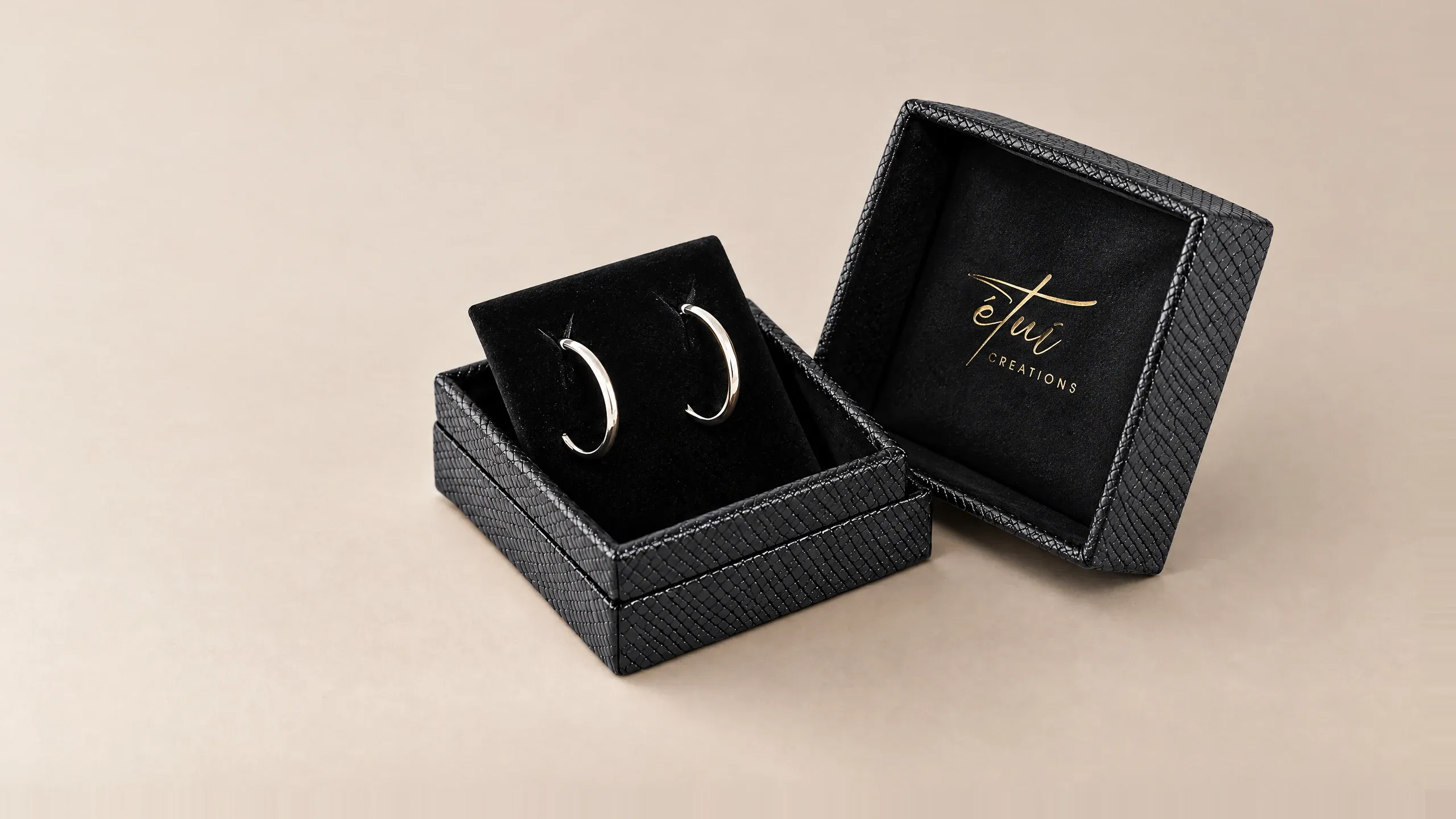 Open box in Black: lid beside the base, hoop earrings in the insert