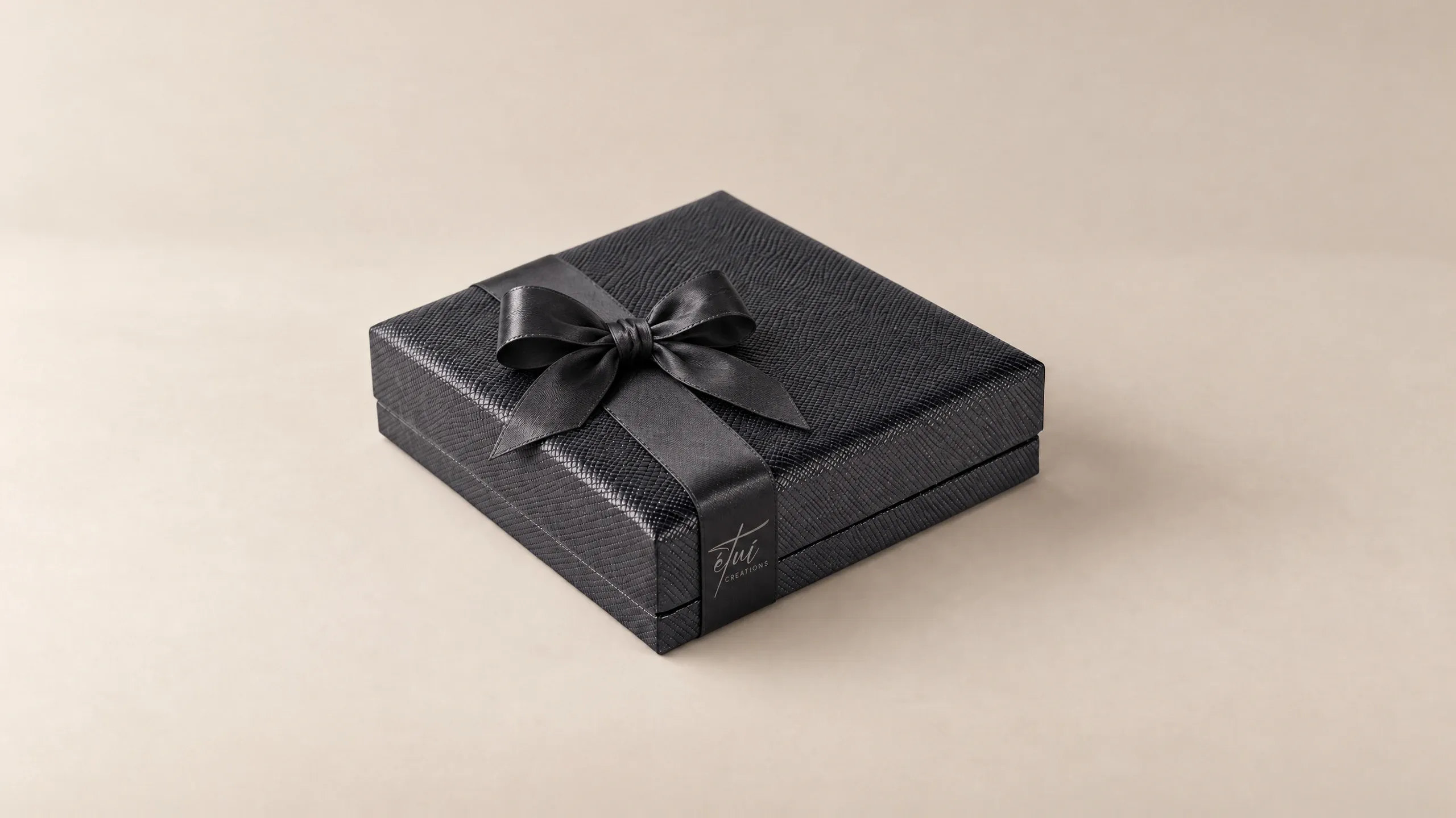 Box in Black with a satin ribbon, the logo on the band