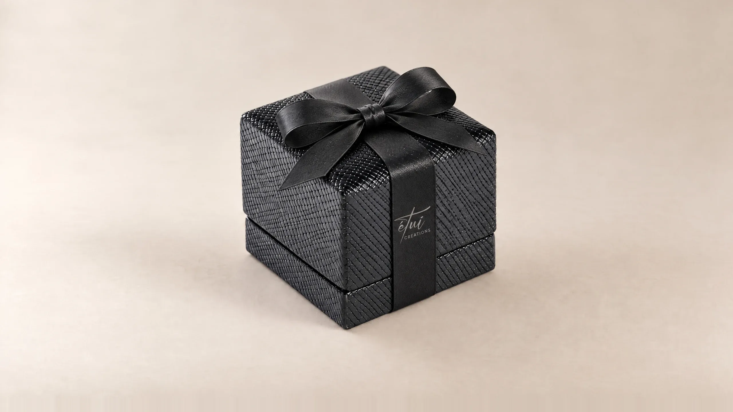 Box in Black with a satin ribbon, the logo on the band